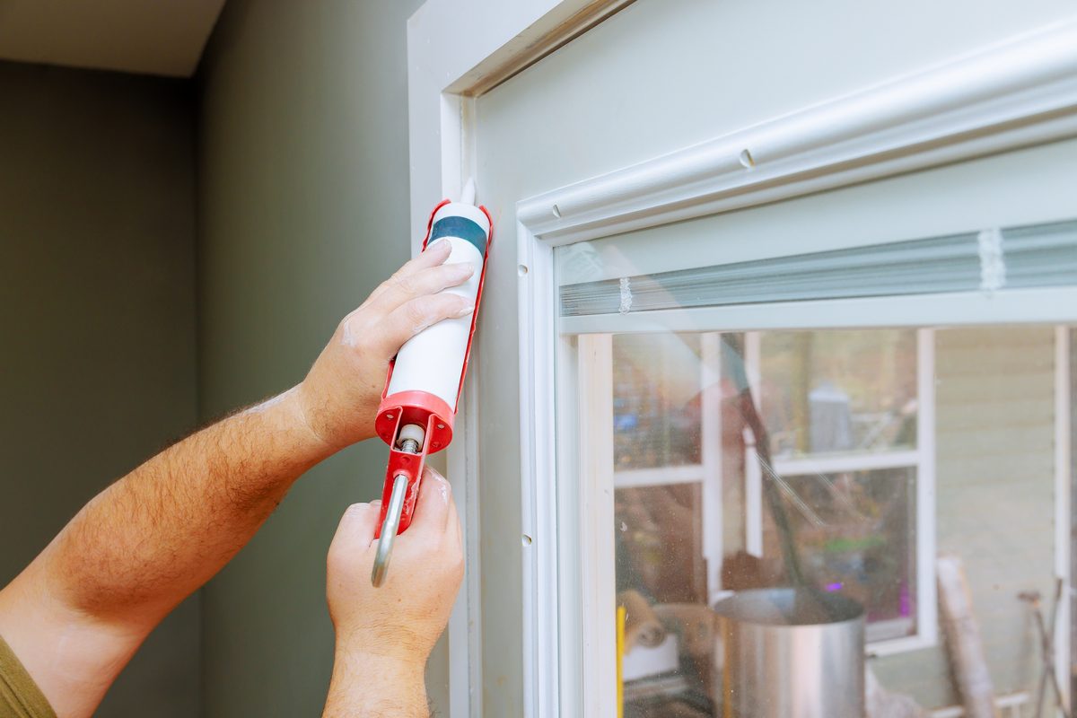 Sealing a window frame gap with caulk to block ant entry points